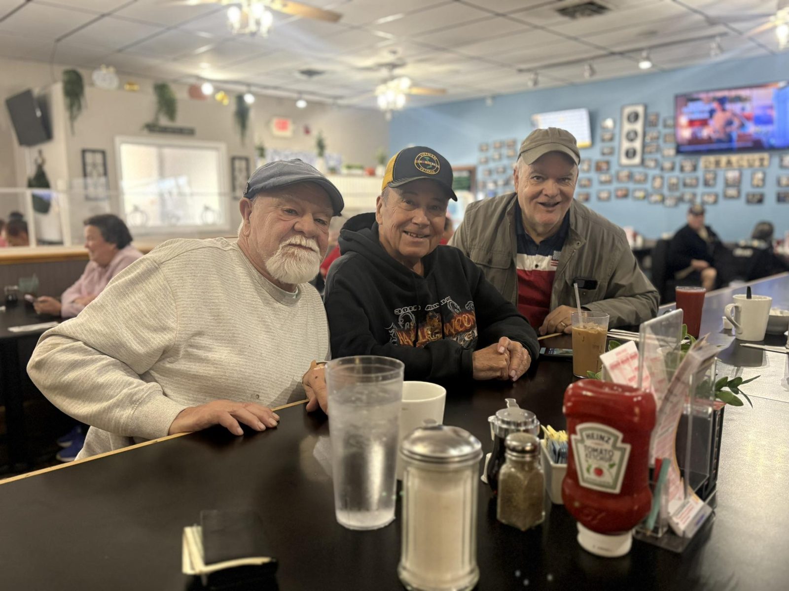 Three regulars sharing coffee and a laugh at the Locals Diner counter