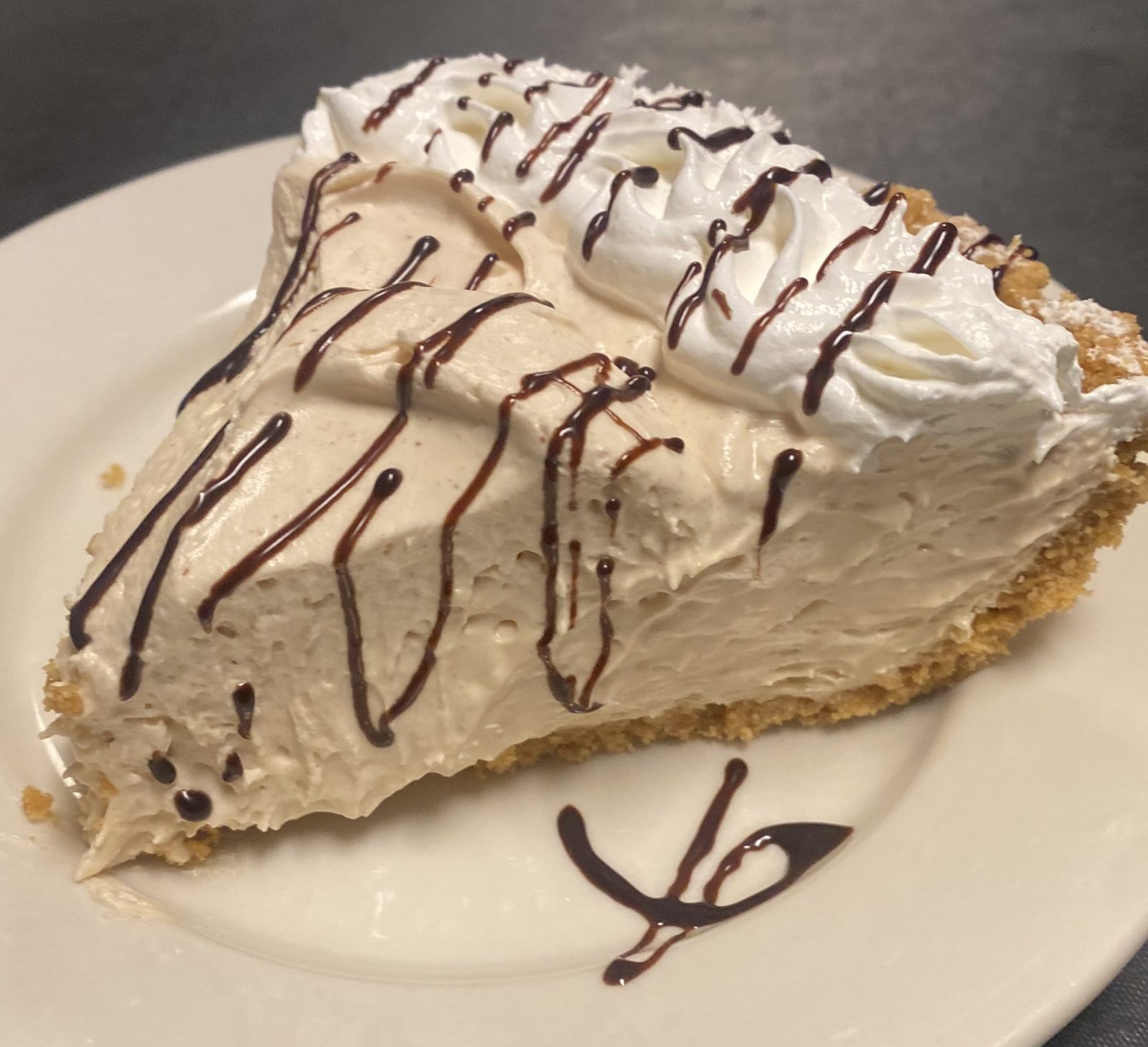A slice of homemade cream pie with chocolate drizzle
